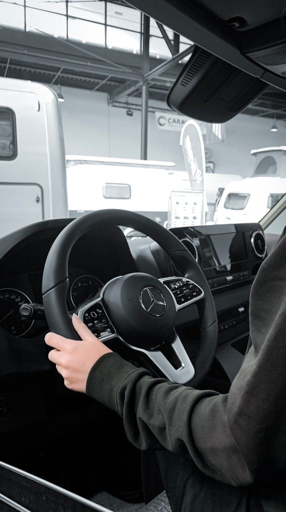 a person sitting in a car with a steering wheel